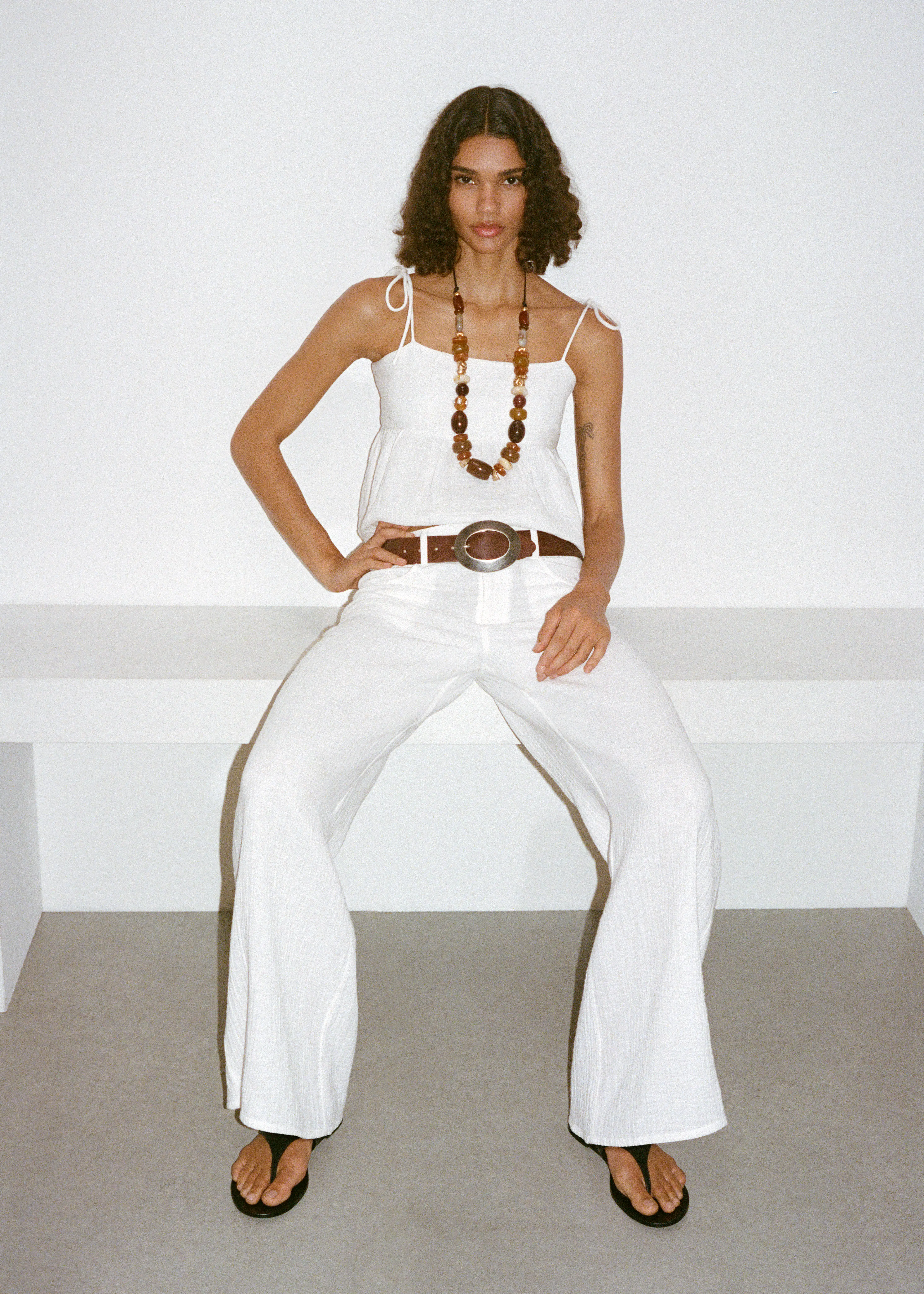 calças e top branco modelo mango cinto castanho sandalias e colar bolas grande