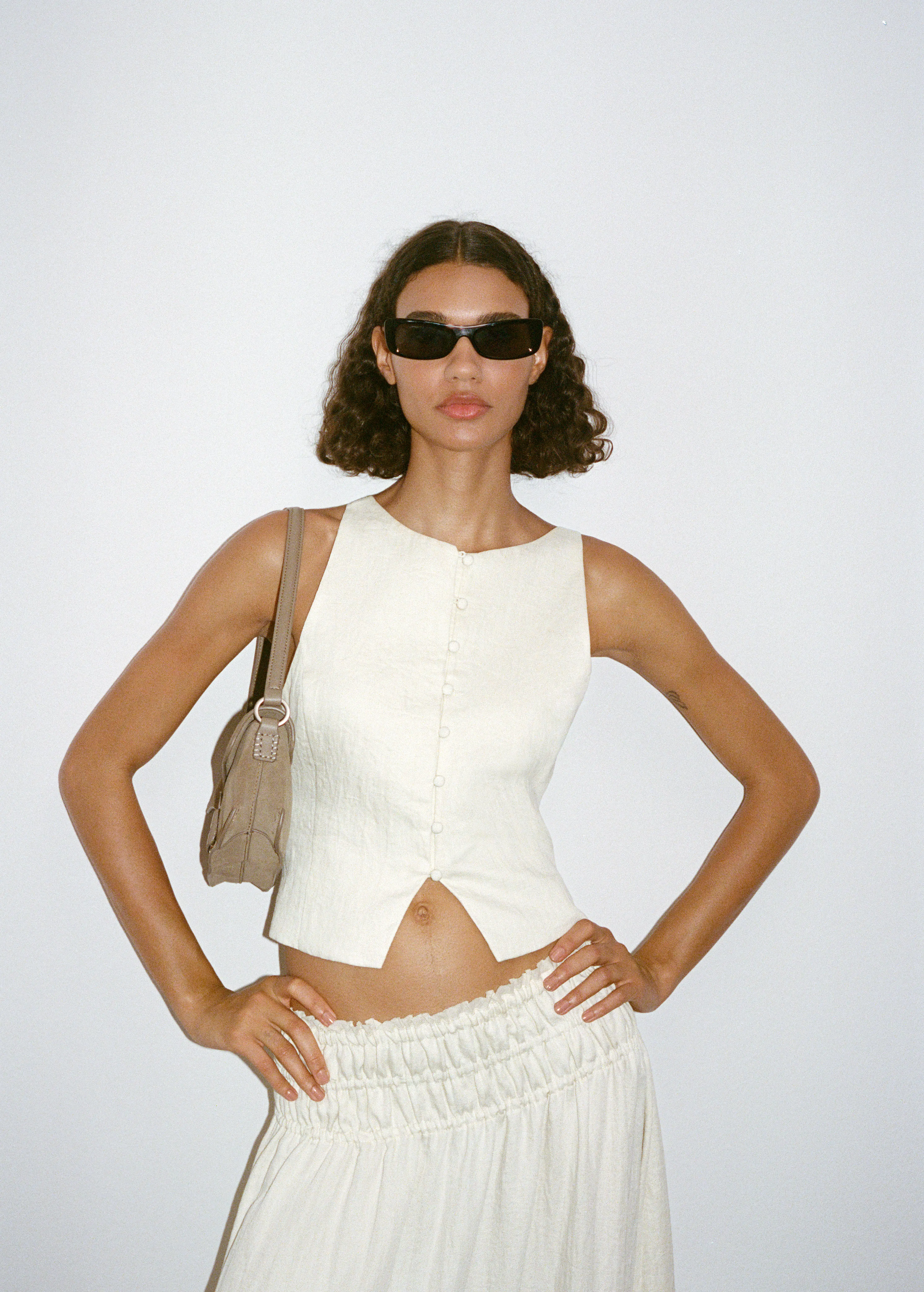 modelo com oculos escuos e mala look branco colete e saia