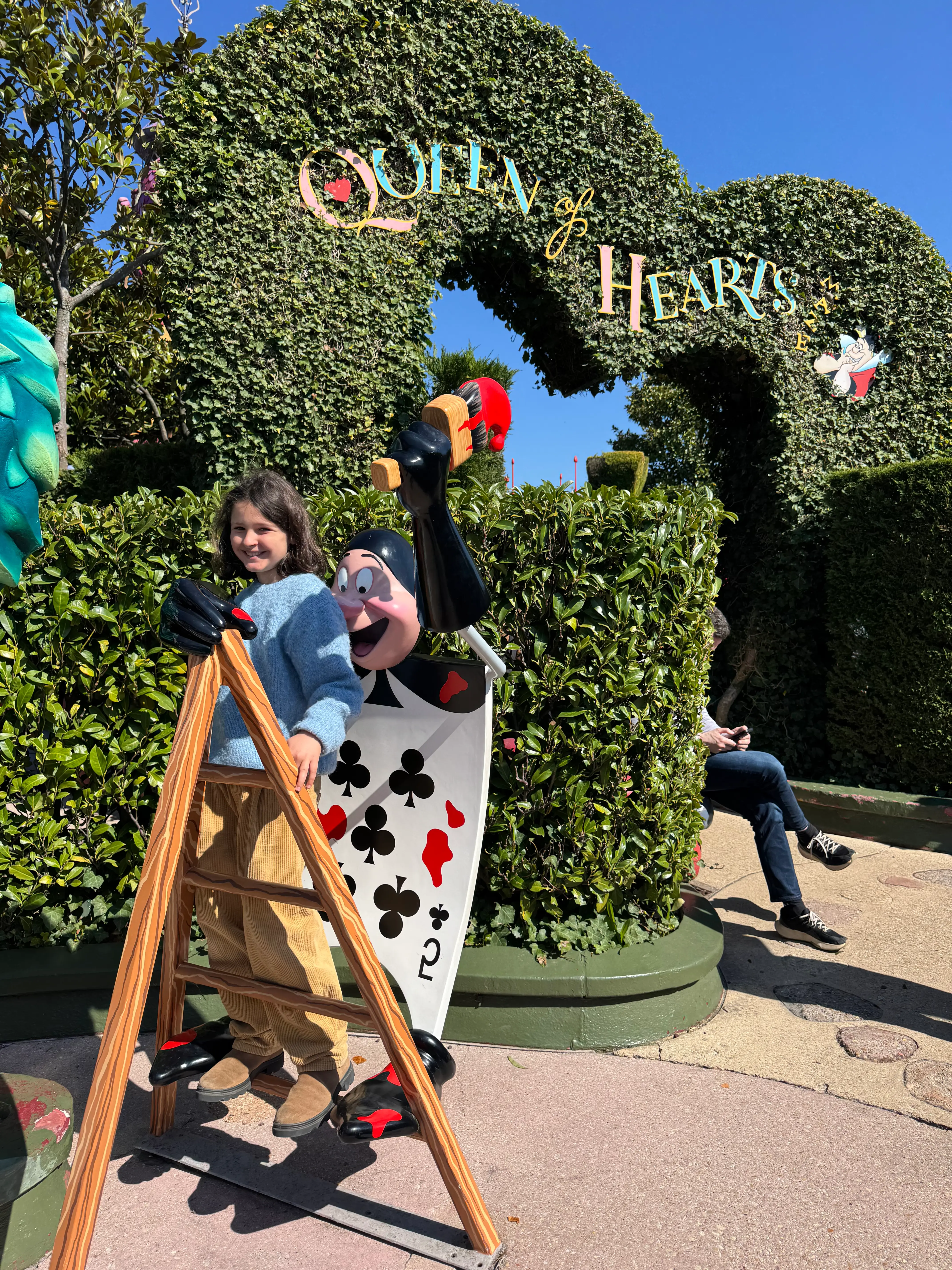 criança na atração da disney da alice no pais das maravilhas com uma carta da rainha de copas