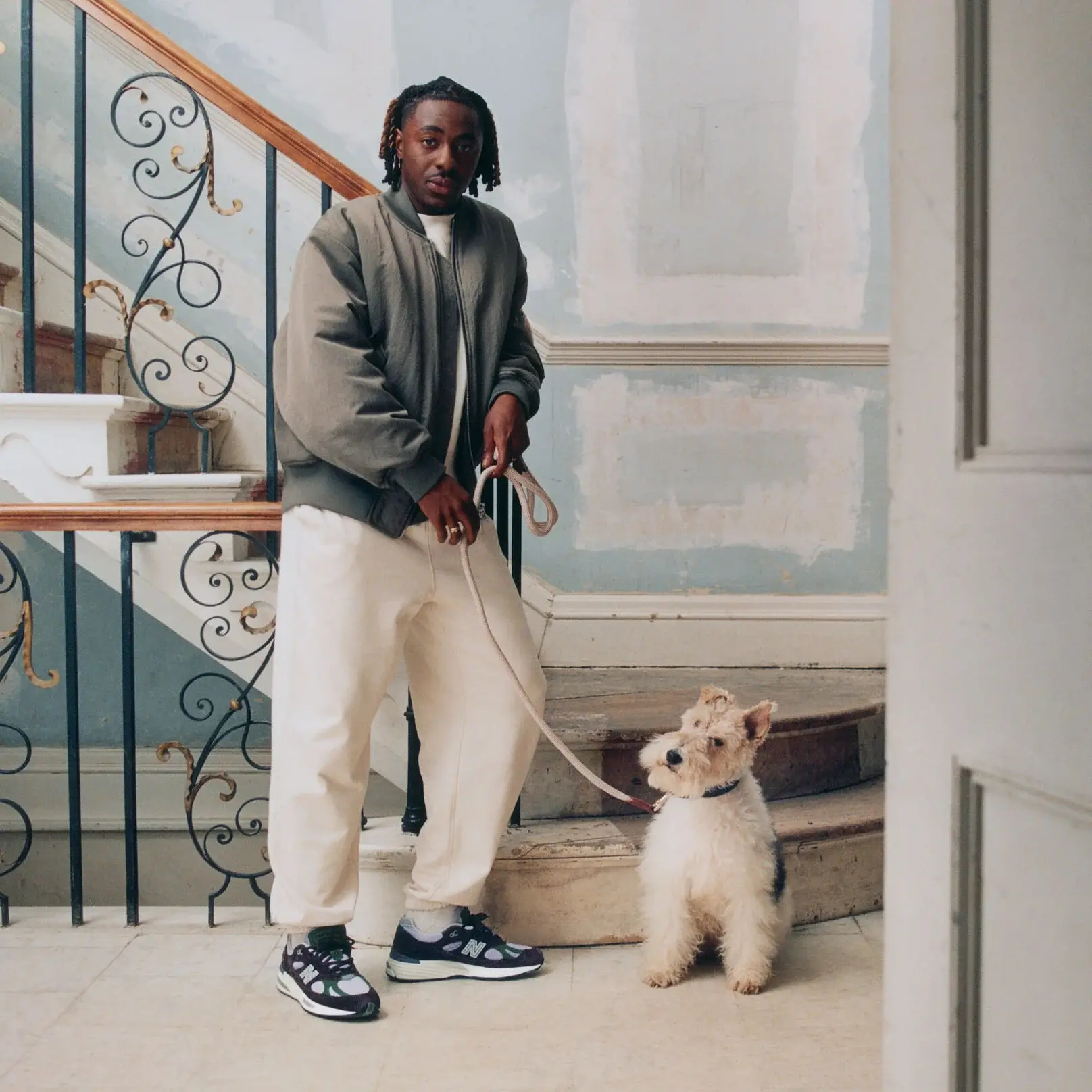 new balance made in uk 991 v2 homem com estilo e um cão num vão de escadas de um prédio antigo e vintage
